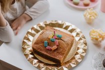 Dall'alto vista di torta di compleanno saporita decorata con candela e caramelle di gelatina messe in forma del numero cinque su tavolo in camera — Foto stock