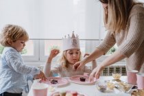 Femme partageant dessert au chocolat sucré avec drapeau sur assiette rose avec les enfants à la maison — Photo de stock