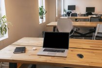 Netbook e mouse posizionati su tavolo in legno con notebook e auricolari wireless in uno spazio di lavoro creativo — Foto stock