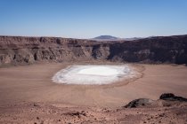 Vista de la superficie de cristal de fosfato sódico blanco colocada dentro del cráter de maar a la luz del sol brillante bajo el cielo azul - foto de stock