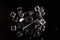 Vue du dessus de l'appareil photo vintage entouré de glaçons montrant le concept de gadget bien préservé sur fond noir — Photo de stock