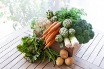 From above of harvest of various ripe vegetables placed in wooden box in garden — Stock Photo