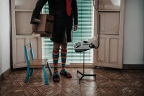 Обрізаний знімок людини з маскою картонної коробки в смугастих шкарпетках, що стоять від ретро друкарської машинки — стокове фото