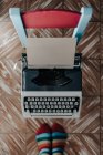 Top view of feet in stripped socks standing near old fashioned typewriter — Stock Photo