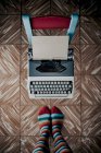 Вид зверху на ноги в роздягнених шкарпетках, що стоять біля старомодного друкарського верстата — стокове фото