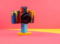 Creative retro photo camera painted with various colors arranged on colorful background — Stock Photo
