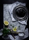Top view of metal plate with plum jelly placed on white fabric on table together with lime slices and bunch of parsley — Stock Photo