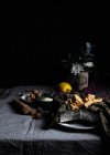 Galletas crujientes frescas en plato con servilleta y nutmegs en tazón colocado en la mesa cubierta con mantel - foto de stock