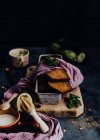 De arriba sabroso pastel de chocolate adornado con pétalos de flores y albahaca y colocado en la mesa con calabacín verde y crema agria en un tazón - foto de stock
