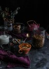 De cima de muesli em jarra de vidro e xícara colocada na mesa com nozes e bagas secas — Fotografia de Stock