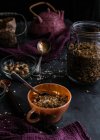 From above of muesli in glass jar and cup placed on table with nuts and dried berries — Stock Photo