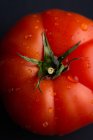 Gros plan angle de tomate rouge mûre placé sur le plat dans la cuisine moderne sur fond noir — Photo de stock