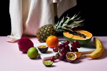 Still life with tropical fruits, sliced papaya, pineapple, pitaya and grapes on marble cutting board — Stock Photo