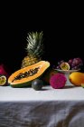 Bodegón con frutas tropicales sobre mantel blanco y fondo oscuro - foto de stock