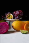 Still life with tropical fruits on white tablecloth and dark background — Stock Photo