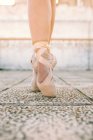 Erntetänzerin in Spitzenschuhen steht auf Zehenspitzen auf verwittertem Steinboden und demonstriert Tanzposition — Stockfoto