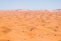 From above picturesque view of car driving on dry sandy dunes in the desert on sunny day in Morocco — Stock Photo