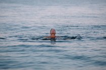Zufriedener männlicher Schwimmer während gesunder aktiver Freizeit in tiefruhiger See, während er nach dem Tauchen bei sonnigem Tag im Urlaub Wasser ausspuckt — Stockfoto
