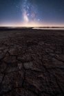 Trockene rissige Oberfläche des Bodens und farbenfroher Sternenhimmel am Horizont — Stockfoto
