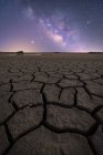 Trockene rissige Oberfläche des Bodens und farbenfroher Sternenhimmel am Horizont — Stockfoto