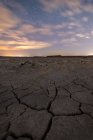 Посуха тріснула неживу землю під барвистим хмарним небом під час заходу сонця — стокове фото