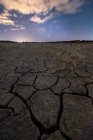 Trockenheit riss leblosen Boden unter buntem bewölkten Himmel bei Sonnenuntergang — Stockfoto