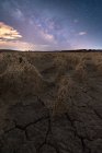 Trockenheit riss leblosen Boden unter buntem bewölkten Himmel bei Sonnenuntergang — Stockfoto