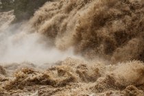Dirty turbulent river stream with splashes of Awash Falls Lodge falling from waterfall in mountainous area — Stock Photo