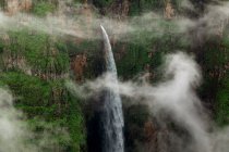 Drone view of amazing landscape of waterfall with rapid water falling down rocky canyon — Stock Photo
