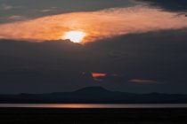 Silhouette der Bergkette und erstaunlicher Sonnenuntergang, der sich im ruhigen Wasser des Sees widerspiegelt — Stockfoto