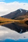 Incroyable paysage écossais de lac calme avec surface réfléchissante miroir montagne avec pic enneigé et ciel nuageux bleu dans la région de Glen Coe — Photo de stock