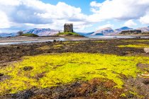 Luminoso paesaggio primaverile con castello medievale in pietra situato sulla collina vicino al fiume nella verde valle delle Highlands scozzesi in una giornata di sole con cielo nuvoloso — Foto stock