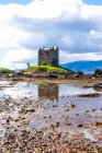 Bright spring landscape with medieval stone castle located on hill near river in green valley in Scottish Highlands in sunny day with cloudy sky — Stock Photo