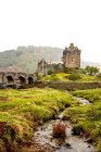 Angolo basso di edificio chiesa invecchiato situato sulla collina illuminato dai raggi del sole contro cielo coperto nelle Highlands scozzesi — Foto stock