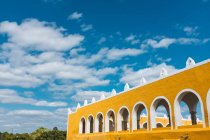 Außenseite der lebhaften gelben Wände mit Bögen in der antiken Stadt Izamal vor blauem Himmel — Stockfoto