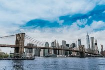 Низкий угол зрелищного городского пейзажа Манхэттена с подвеской Бруклинского моста и небоскребами на фоне удивительного неба — стоковое фото