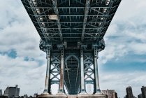 Bajo ángulo de torres de piedra con arcos puntiagudos de puente colgante de Brooklyn en día nublado - foto de stock