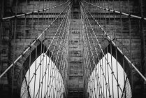 Angolo basso di torri in pietra con archi a sesto acuto di ponte di Brooklyn nella giornata nuvolosa — Foto stock