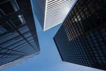 Von unten moderne Wolkenkratzer mit gläsernen Spiegelwänden vor blauem Himmel — Stockfoto