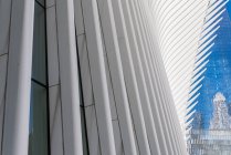 Знизу сучасних хмарочосів зі скляними дзеркальними стінами та футуристичною конструкцією на тлі блакитного неба — стокове фото