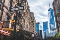 Низкий угол современных горизонтов со стеклянными фасадами и дорожным знаком в одну сторону на улице Манхэттена — стоковое фото