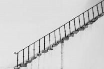 Black and white shabby stairway with concrete steps and metal banister on background of white wall — Stock Photo