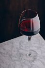 Cristal verre classique de vin rouge placé sur une table en marbre sur fond noir — Photo de stock