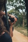 Joyeux voyageur masculin avec appareil photo professionnel prenant des photos de la faune pendant le safari — Photo de stock