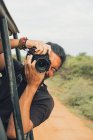Homem viajante feliz com câmera fotográfica profissional tirando fotos da vida selvagem durante o safári — Fotografia de Stock