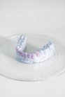 Крупним планом білий зуб відлитий з розфарбованими зубами, розміщеними на білій поверхні в сучасній лабораторії — стокове фото