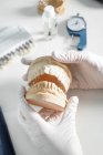 De cima de colheita dentista anônimo em luvas médicas que trabalham com prótese dentária em laboratório moderno — Fotografia de Stock