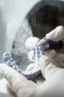 De cima de cultura dentista anônimo em luvas médicas moagem prótese dentária com ferramenta profissional enquanto trabalhava em laboratório moderno — Fotografia de Stock