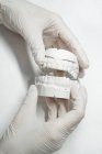 Анонімний стоматолог в медичних рукавичках, що тримає зубний протез в сучасній лабораторії — стокове фото