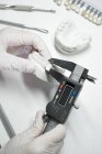 De cima de cultura ortodontista anônimo usando paquímetro para medir enquanto trabalhava com modelo de mandíbula dentária em laboratório — Fotografia de Stock